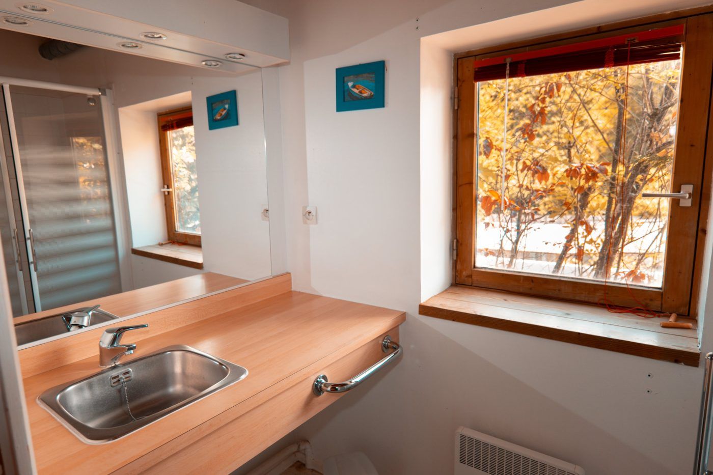 Bathroom with a wooden vanity top and a window onto the autumn trees