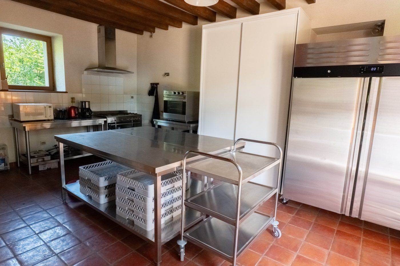La cuisine avec son îlot inox, son chariot de service et son armoire réfrigérée professionnelle