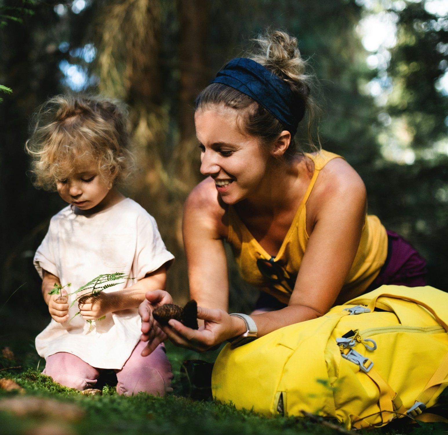 A mother and her little girl picking ferns in the forest