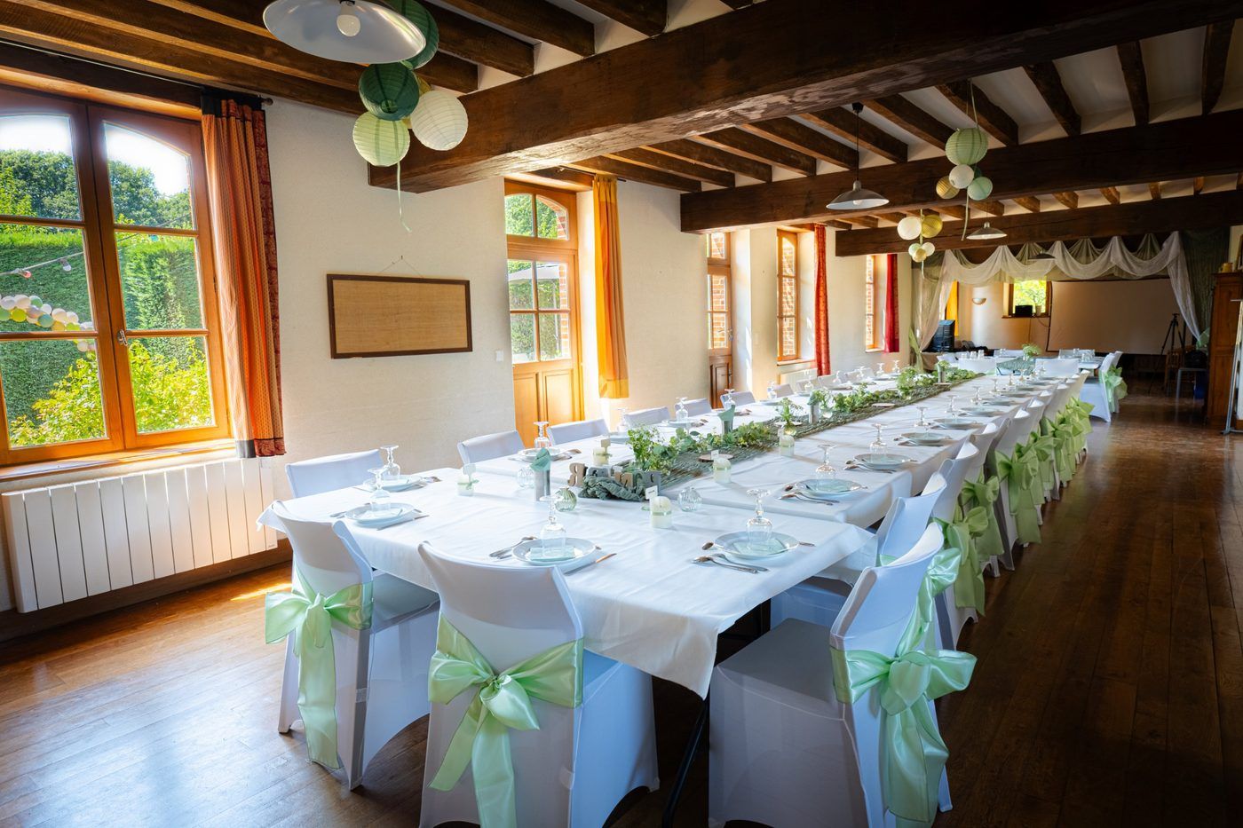 La salle décorée pour un mariage, housses de chaises et nœuds verts