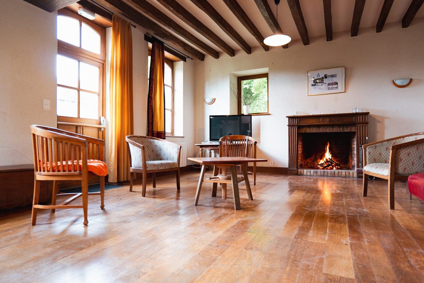 Le salon de la maison forestière : parquet, poutres et feu de cheminée