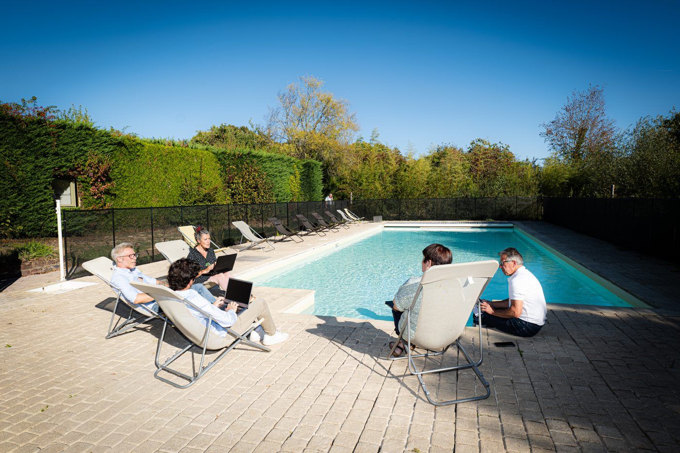 A team working on laptops beside the pool